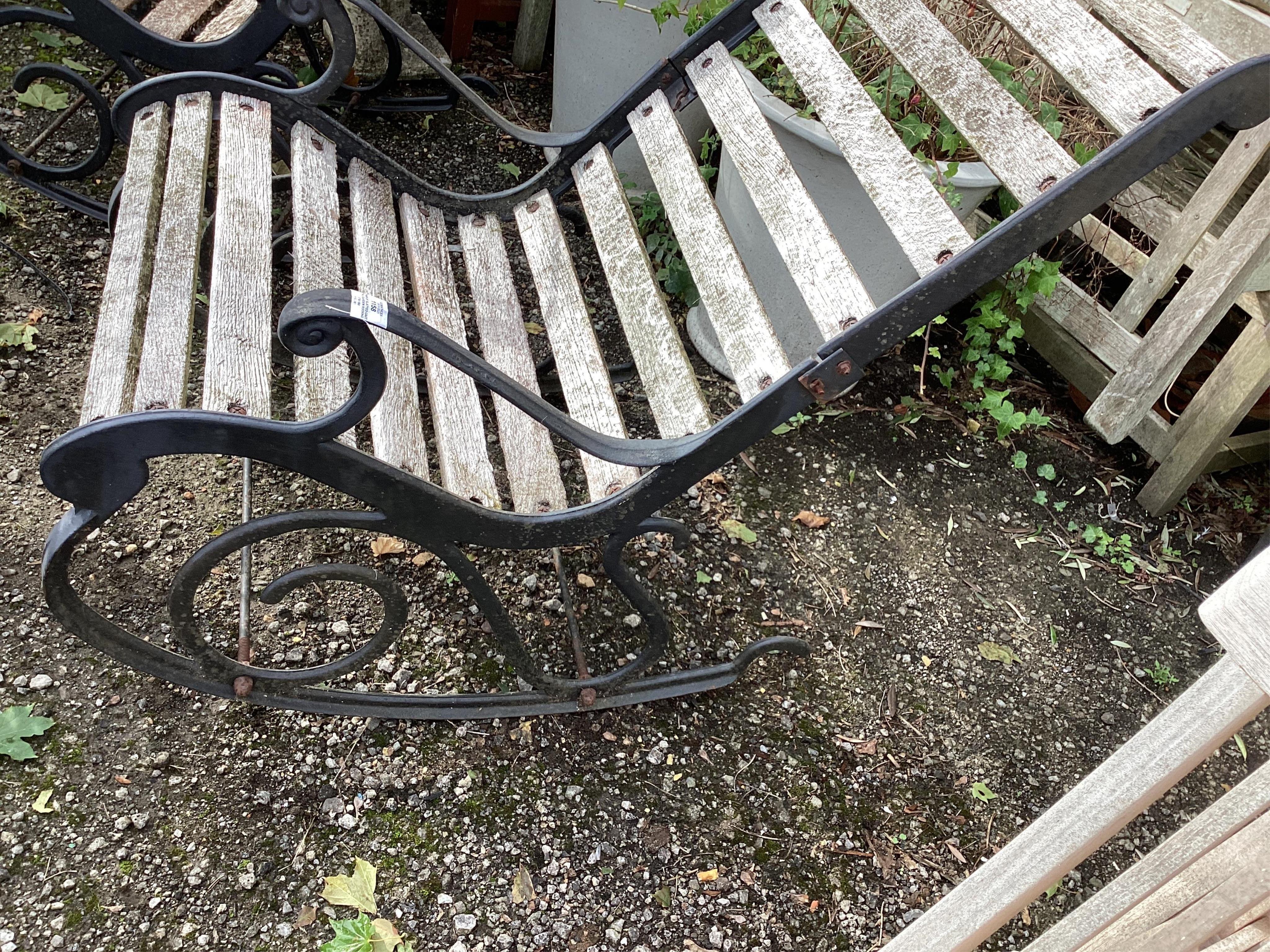 A pair of slatted cast metal garden rocking chairs